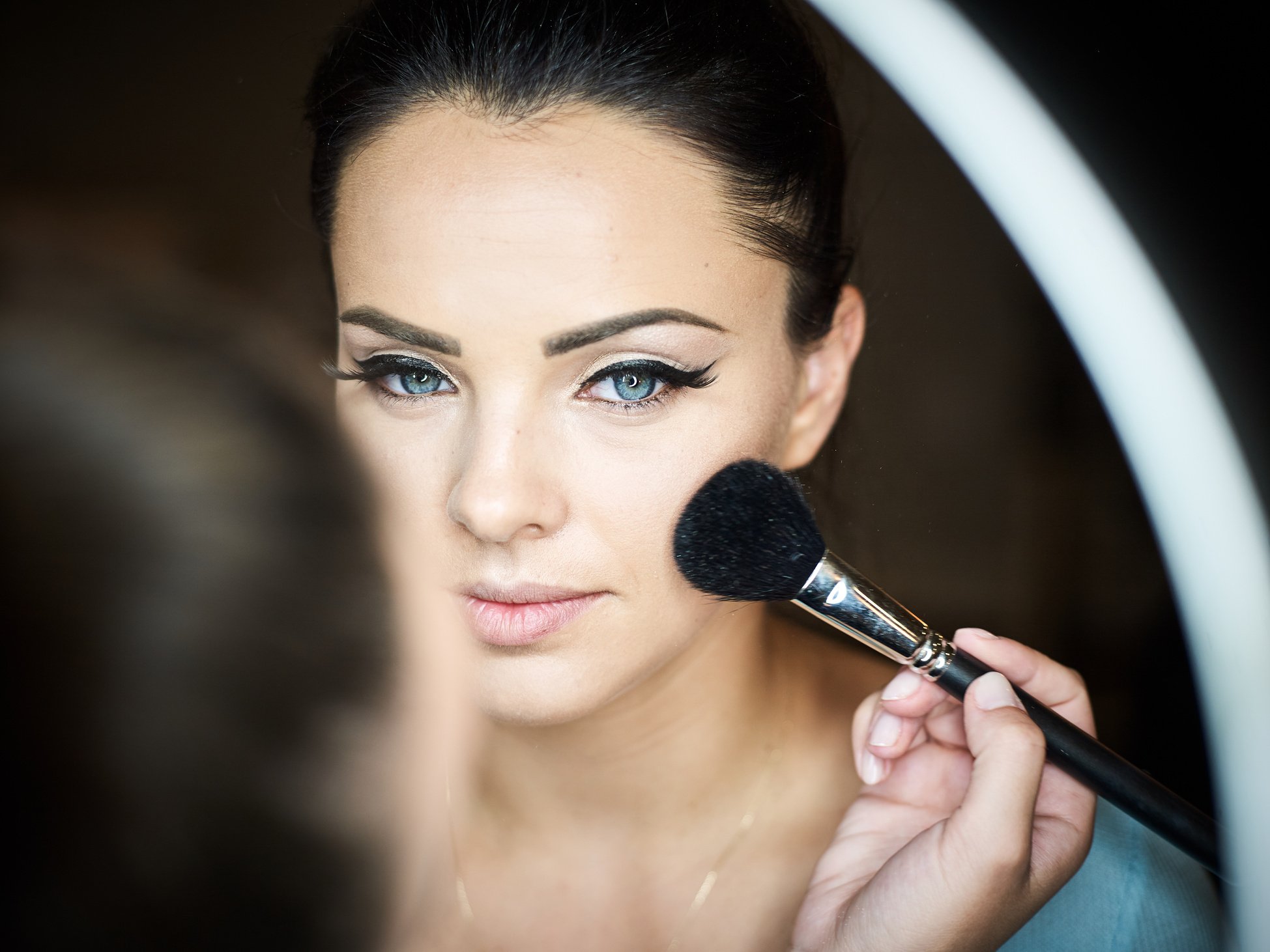 Make up artist doing professional make up of young woman.